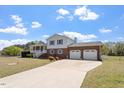 Exterior showcasing a two-story home with a well-maintained lawn, brick accents, and a two-car garage at 153 Glenn Oak Dr, Sanford, NC 27332