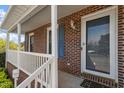 Front porch with brick columns, white railing, and a door with glass panel at 153 Glenn Oak Dr, Sanford, NC 27332