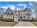 Beautiful two-story home with a manicured lawn and a two-car garage on a sunny day at 215 Mystic Pine Pl, Apex, NC 27539