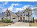 Charming two-story home featuring a well-manicured lawn, an attached garage, and stone accents at 215 Mystic Pine Pl, Apex, NC 27539