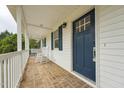 Inviting front porch with rocking chairs, brick flooring, and a blue front door at 327F Bobbitt Rd, Clayton, NC 27520