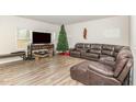 Comfortable living room with a large brown leather sofa, seasonal decor, and wood-look floors at 609 Embrun Run, Wendell, NC 27591