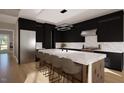 Modern kitchen with sleek black cabinetry, waterfall island, stainless steel appliances, and marble backsplash at 95 Cherry Bark Dr, Youngsville, NC 27596