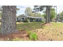 Attractive single-story gray home featuring mature trees and landscaped front lawn at 1 Greenfield Ct, Durham, NC 27705
