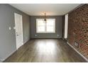Spacious living room with updated floors, a brick accent wall, and modern lighting at 1212 St. Marys Rd, Hillsborough, NC 27278