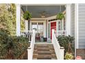 Inviting covered front porch with red door, hanging ferns, seating, and freshly painted railing at 1300 Marshall Farm St, Wake Forest, NC 27587