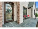 Inviting front porch with slate flooring, brick columns, comfortable seating, and a decorative wreath on the front door at 1801 Clifton Pines Dr, Cary, NC 27519