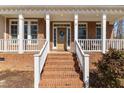 Inviting brick home featuring a charming front porch and a classic wooden door with decorative wreath at 2021 Terri Creek Dr, Fuquay Varina, NC 27526