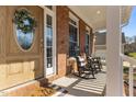 Inviting front porch with brick accents, rocking chairs, and a charming front door with a decorative wreath at 2021 Terri Creek Dr, Fuquay Varina, NC 27526