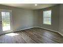 Bright bedroom with a wood-look floor, white trim and window, and a glass door leading to the outside at 255 Constellation Ct, Benson, NC 27504