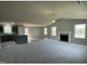 Spacious living room with plush carpeting, fireplace, ceiling fan, and ample natural light filtering through multiple windows at 255 Constellation Ct, Benson, NC 27504