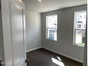 Well-lit bedroom showcasing dark floors, neutral walls, and two windows offering a pleasant view of the outside at 3012 Honeymyrtle Ln, Durham, NC 27703
