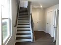 Entryway with staircase, hardwood flooring, white walls, and a door, creating a bright and welcoming atmosphere at 3012 Honeymyrtle Ln, Durham, NC 27703