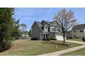 Charming two-story home with gray siding, manicured lawn, and mature landscaping at 404 Braxman Ln, Holly Springs, NC 27540