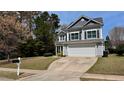 Charming two-story home showcasing a manicured lawn, blue siding, and attached two-car garage at 404 Braxman Ln, Holly Springs, NC 27540