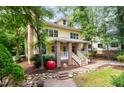 Lovely two-story yellow home with brick porch, lush trees, and unique red apple sculpture at 407A Hillsborough St, Chapel Hill, NC 27514