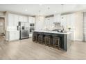 Bright kitchen boasts white cabinets, stainless steel appliances, a large island with seating, and stylish backsplash at 557 Freedom Trail Dr, Willow Springs, NC 27592