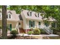 Traditional home featuring dormer windows, green shutters, and brick accents, set in a lush, wooded landscape at 63 Tally Ho Dr, Selma, NC 27576