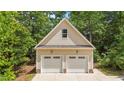 A two-car garage with a peaked roof, complemented by tan siding and surrounded by lush greenery at 63 Tally Ho Dr, Selma, NC 27576