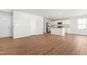 Open-concept living area with wood floors, leading to a modern kitchen with white cabinets at 653 Corvair Ln, Wendell, NC 27591