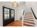 Welcoming entryway with hardwood floors, staircase, stylish light fixture, and bathroom view at 7950 Country Knoll Rd, Bahama, NC 27503