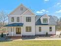 Charming exterior featuring gray siding, black trim windows, and a covered porch with brick accents at 7950 Country Knoll Rd, Bahama, NC 27503