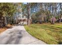 View of the back of the home showing a long driveway, and a wooded lot providing a secluded feel at 100 Lochberry Ln, Cary, NC 27518