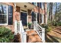 Inviting front porch features brick steps with white railings and a classic black door with decorative accents at 100 Lochberry Ln, Cary, NC 27518
