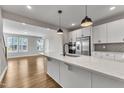 Bright kitchen with white cabinets, stainless appliances, quartz counters, and pendant lighting at 1234 Coach Station Alley # 101, Raleigh, NC 27601
