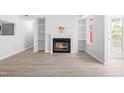Open-concept living room with built-in shelving and a cozy fireplace at 1300 Hillbrow Ln # 204, Raleigh, NC 27615