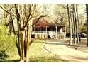 View of the charming single story home with inviting front porch and driveway surrounded by mature trees at 1409 Keogh St, Burlington, NC 27215