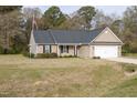 A quaint tan house with a lawn, American flag, and a two-car garage at 151 Goose Creek Cir, Dunn, NC 28334