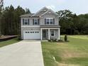 Charming two-story home with gray siding, stone accents, attached garage, and green front lawn at 4012 Kingcraig Ln, Zebulon, NC 27597