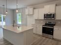 Bright kitchen features an island with sink, stainless steel appliances, and white cabinets at 4012 Kingcraig Ln, Zebulon, NC 27597