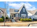Two-story home showcasing stone accents, a covered porch, and landscaped front yard with a sidewalk at 405 Daisy Grove Ln, Holly Springs, NC 27540