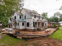 New construction two-story home with a brick base, black framed windows, and ladder access points surrounded by raw land at 5107 Hearth Dr, Raleigh, NC 27609