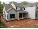 A new construction home with a covered back patio that has exposed wood support beams on a muddy lot at 5107 Hearth Dr, Raleigh, NC 27609