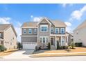 Charming gray two-story home with stone accents, covered porch, manicured lawn and attached two-car garage at 715 White Oak Pond Rd, Apex, NC 27523