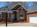 Detailed close-up of brick home's entry with an arched window and manicured landscaping at 805 Lee St, Gibsonville, NC 27249