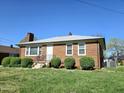 Red brick home with trimmed bushes, a white door, and a gray roof at 807 Everett St, Burlington, NC 27215