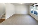 Spacious empty room with neutral carpet, a staircase, and plenty of natural light from a window at 106 Canvasback Dr, Durham, NC 27704