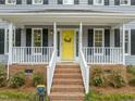 Close up of front porch and yellow front door, brick stairs with white railings, and well maintained landscaping at 2032 Stoneglen Ln, Raleigh, NC 27603