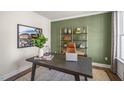 A modern office showcases a dark wooden desk, a leather chair, and stylish decorative elements on an olive accent wall at 213 Umstead St, Sanford, NC 27330
