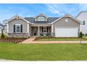 Charming home featuring a stone facade, well-manicured lawn, and inviting brick walkway at 312 Providence Creek Dr, Fuquay Varina, NC 27526