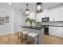 Well-lit kitchen with a gray island, white cabinets, stainless appliances, and elegant pendant lighting at 364 Church St, Morrisville, NC 27560