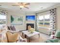 Cozy living room featuring plush seating, fireplace, ceiling fan, and large windows with natural light at 39 Atherton Circle, Angier, NC 27501