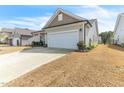 View of the two-car garage and a well-maintained lawn with carefully placed plants and shrubbery at 4102 Catfish Way, Durham, NC 27703