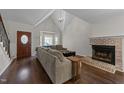 Cozy living room with vaulted ceilings, a brick fireplace, hardwood floors, and a bay window at 4724 Worchester Pl, Raleigh, NC 27604