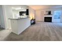 Open living area with a fireplace and a breakfast bar flowing to the kitchen at 4907 Hollenden Dr # 105, Raleigh, NC 27616