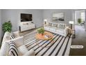 Bright staged living room featuring a white couch, chairs and striped area rug at 5620 Hamstead Xing, Raleigh, NC 27612